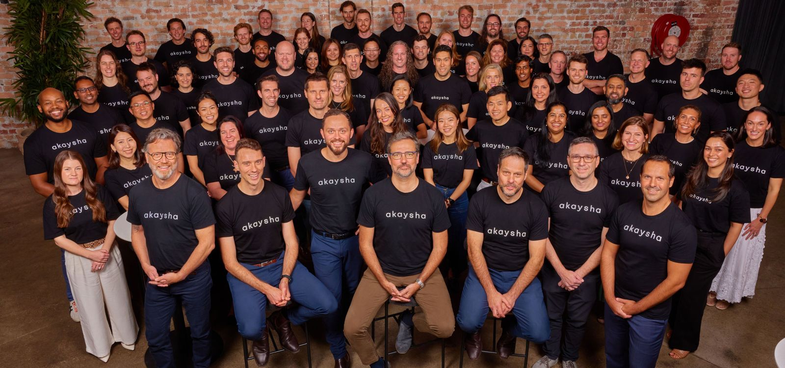 All of the Akaysha Energy team posing for a portrait in front of a brick wall