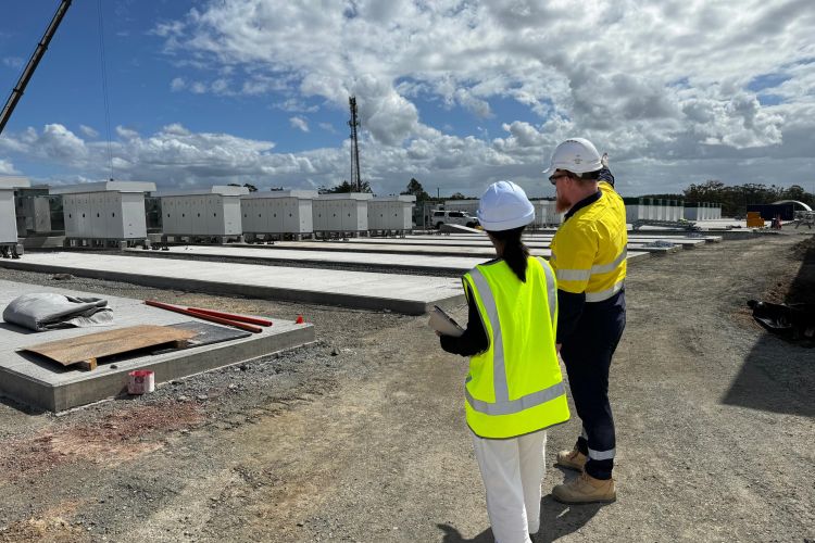 Seven people wearing PPE standing on a concrete slab overlooking a large construction site